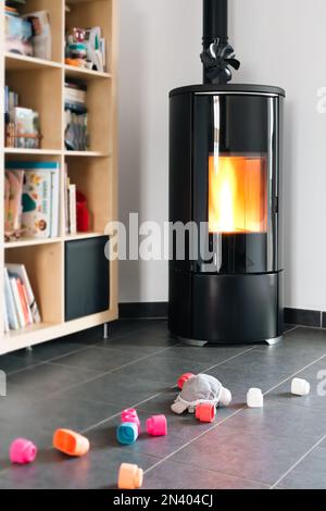 Pellet stove with some toys in front, with flames and library Stock Photo