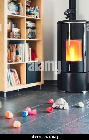 Pellet stove with some toys in front, with flames and library Stock Photo