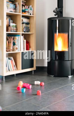 Pellet stove with some toys in front, with flames and library Stock Photo