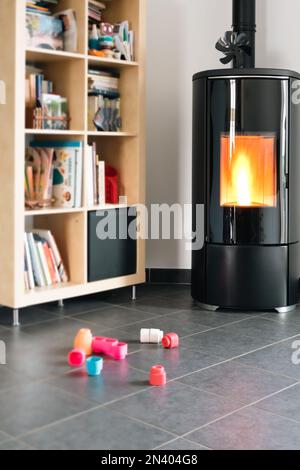 Pellet stove with some toys in front, with flames and library Stock Photo