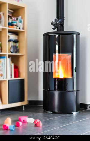 Pellet stove with some toys in front, with flames and library Stock Photo