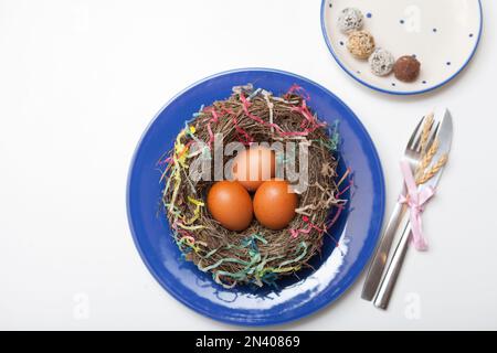 nest with eggs on blue plate. Happy Easter. Stylish white table, flat lay. Natural eggs spring Stock Photo