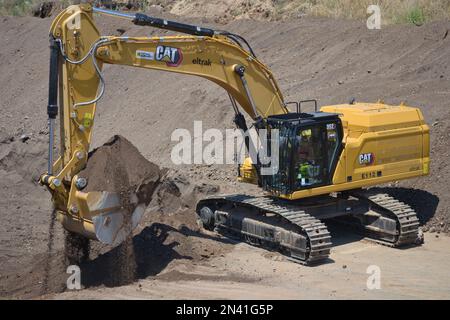 Caterpillar excavator working. Loading truck on huge mining site. Stock Photo