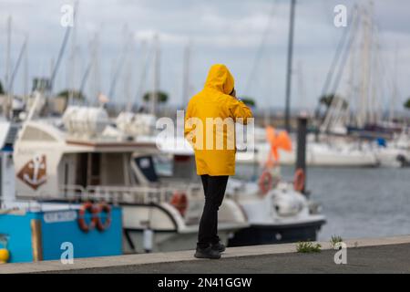 man in yellow oilskin walking along the fishing port Stock Photo