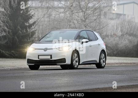 White Volkswagen ID3 electric car driving on street on a foggy day of winter. Salo, Finland. January 21, 2023 Stock Photo