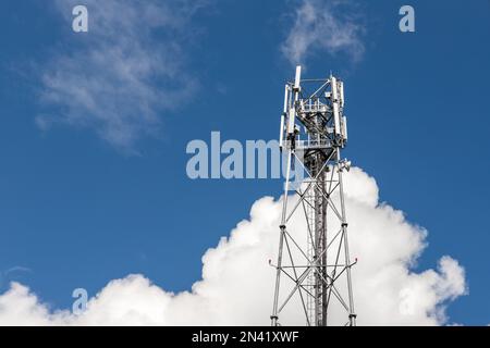 Bottom perspective pov of modern metal steel mobile 5g network wireless telecom tower against clear blue sky background on bright day. Microwave Stock Photo