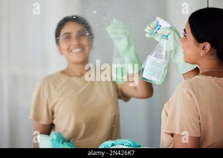 Happy, woman and cleaning mirror with smile, spray bottle and soap, housekeeping in home or hotel. Housework, smudge and housekeeper or cleaner Stock Photo