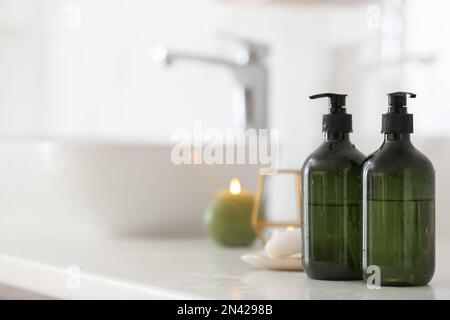 Green soap dispensers on countertop near sink in bathroom. Space for text Stock Photo