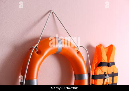 Orange life jacket and lifebuoy on pink background. Rescue equipment Stock Photo