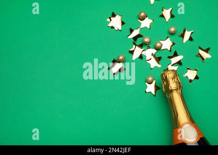 Flat lay composition with confetti and bottle of champagne on green background. Space for text Stock Photo