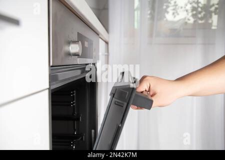 A man opens a modern oven door with child protection function. Stock Photo