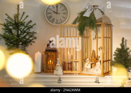 Christmas lanterns and other decorations on mantelpiece in room Stock Photo