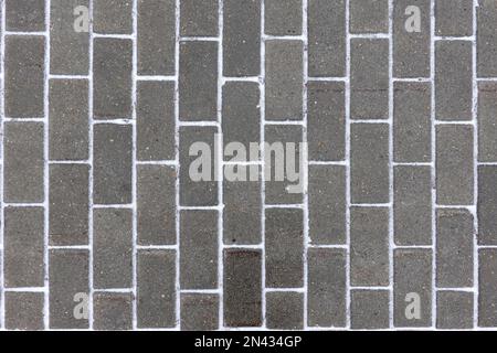 Dark gray paving slabs as background with snow stipes between blocks top view close up Stock Photo