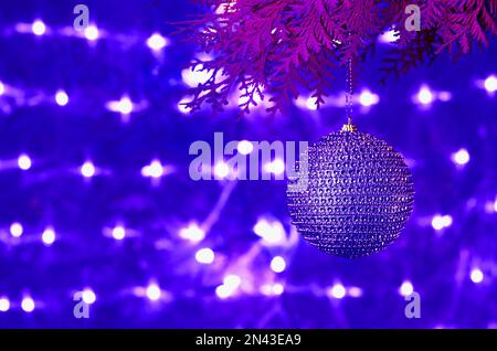 Christmas card, blue shiny ball on a coniferous branch on a blue glowing background. Stock Photo
