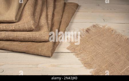 A stack of coarse peasant cloth - burlap and a tarpaulin on a wooden table. Rustic style image. Stock Photo