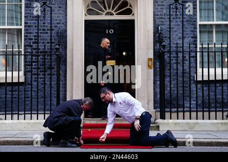 Downing Street staff lay out the red carpet in front of 10 Downing Street, London, ahead of the arrival of Ukrainian President Volodymyr Zelensky, for a bilateral meeting with Prime Minister Rishi Sunak, during his first visit to the UK since the Russian invasion of Ukraine. Picture date: Wednesday February 8, 2023. Stock Photo