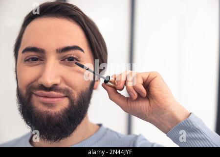 Pleased transgender person using the eye cosmetics Stock Photo