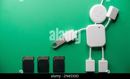A closeup top view of a 4-port USB hub and three black SD cards on a green background Stock Photo