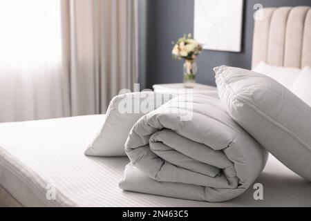 Soft folded blanket and pillows on bed indoors Stock Photo