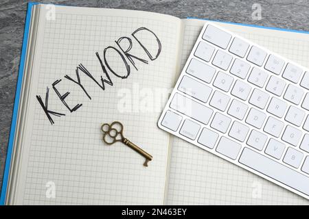 Key, notebook and computer keyboard on table, flat lay. Keyword concept Stock Photo