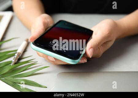 MYKOLAIV, UKRAINE - JULY 9, 2020: Woman holding Iphone 11 with lock screen at table, closeup Stock Photo