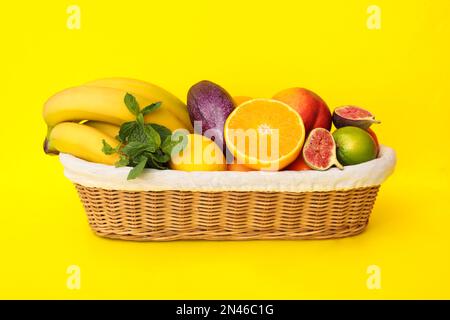 Assortment of fresh exotic fruits in basket on yellow background Stock Photo