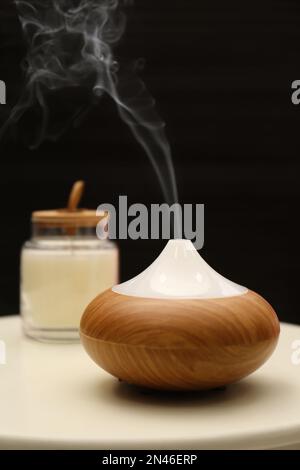 Aroma oil diffuser on table near black wall Stock Photo