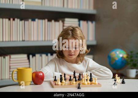 Concentrated serious boy developing chess gambit, strategy ,playing board  game to winner clever concentration and thinking child while playing chess.  Learning, tactics and analysis concept. Free Photo