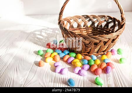 Basket with scattered colorful Easter eggs on a white wooden table Stock Photo