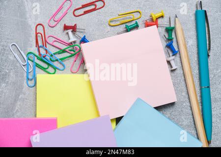 Bundles of multicolored stickers for written notes with chancellery on gray background Stock Photo