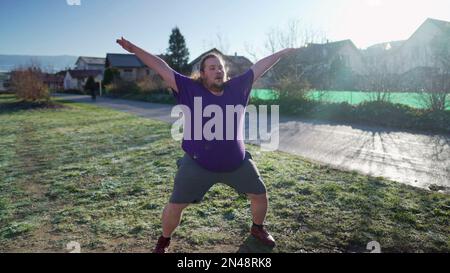 One overweight young man doing jumping jacks outdoors in the cold. Back to fitness motivational discipline concept. Person exercising Stock Photo