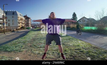 One overweight young man doing jumping jacks outdoors in the cold. Back to fitness motivational discipline concept. Person exercising Stock Photo