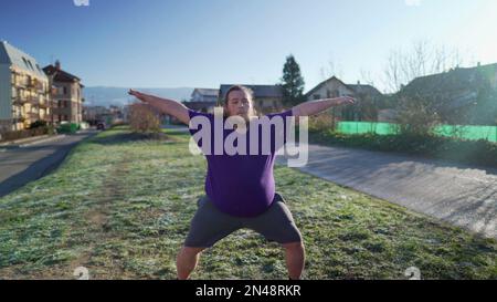 One overweight young man doing jumping jacks outdoors in the cold. Back to fitness motivational discipline concept. Person exercising Stock Photo