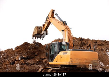 Crawler excavator scoops the earth with a bucket. Earthmoving works, digging on a construction site Stock Photo