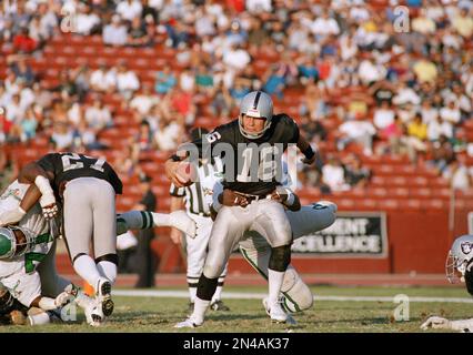 Los Angeles running back Marcus Allen (32) tries to break away from  Washington Redskins Dave Butz (65) as Rich Milot (57) looks on during the  first half of their game at R.F.K.