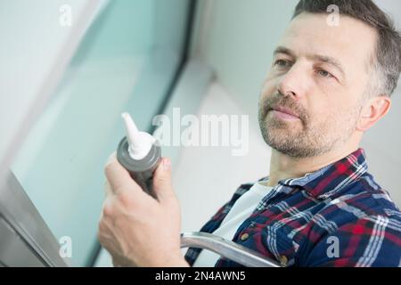 man with silicone sealant and caulking gun in hands Stock Photo