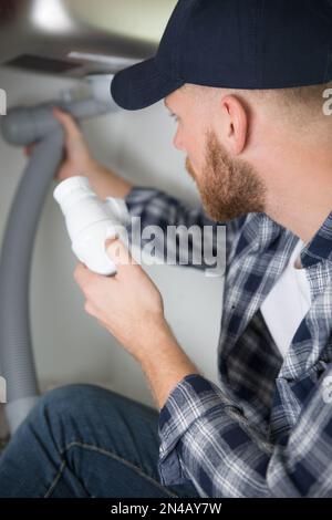 plumber fixes sink siphon by two pipe-wrenches in bathroom Stock Photo