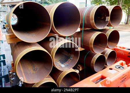 Rusted Pipes with Threaded Ends in Stacks with Green Straps on Construction Site, Horizontal View View Stock Photo