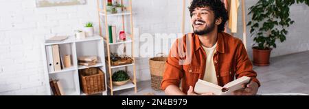 Positive indian man holding book at home, banner,stock image Stock Photo