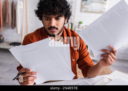 Focused indian copywriter working with papers at home,stock image Stock Photo