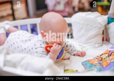 The legs of a newborn baby. Baby pink baby legs that learn to crawl in a crib with a white sheet. a tiny unrecognizable girl moves in a crib. Defocuse Stock Photo