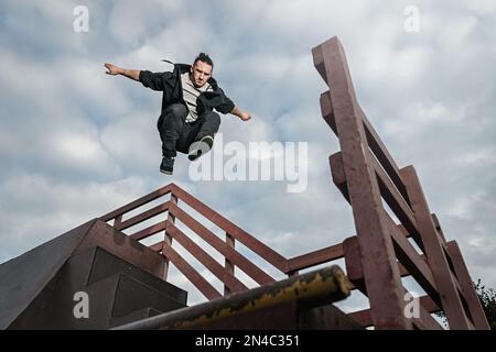 Man doing parkour in city. Athlete practicing freerunning trick. Stock Photo