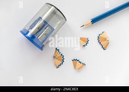 Blue pencil with pencil sharpener and its shavings on white paper background. Stock Photo