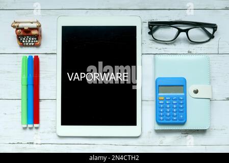 Business concept. Top view of colorful pen, calculator,glasses,pen,notebook and tablet written with Vaporware on white wooden background. Stock Photo