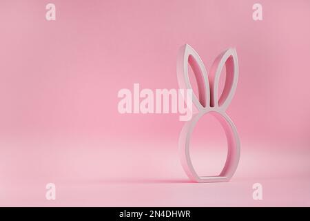 Wooden easter bunny figurine on the pink background, easter minimal concept with copy space Stock Photo
