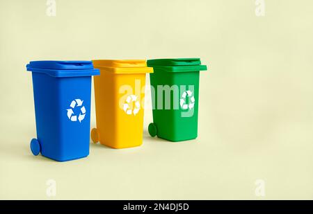 Blue, yellow and green container for separate plastic, paper and organics garbage collection, isolated on the yellow background with copy space, waste Stock Photo