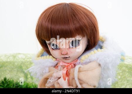 modern makeup doll face portrait toy red hair girl lying in green  background Stock Photo - Alamy