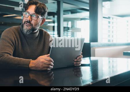 One modern man working on laptop at the desk in empty office or coworking space with light in background. Scared for security account. Smart lifestyle Stock Photo