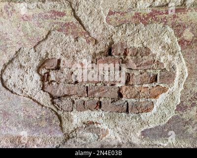 Texture of old brick wall with collapsed plaster. Background of shabby building surface. Destroyed brick wall with fallen plaster. Weathered surface. Stock Photo