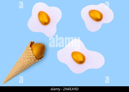 Waffle ice cream cone with a hidden golden Easter egg and scrambled eggs with colored eggs like clouds on a blue background, concept, flat layout, min Stock Photo
